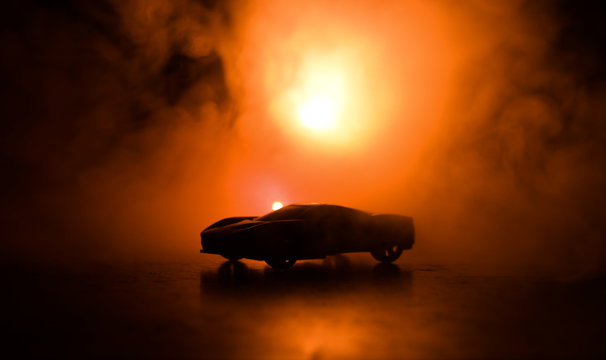 The car in the shadows with glowing lights in low light, or silhouette of sport car dark background