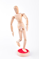Action of wooden dummy on white background. Wooden human figurine standing on red stand over white background. Wooden human dummy is sportsman. Running wooden dummy.
