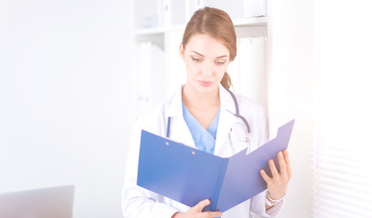 Smiling female doctor with a folder in uniform standing at hospital