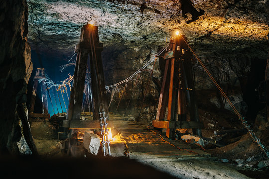 Old Wooden Bridge In Scary Abandoned Underground Limestone Mine Cave Or Tunnel Or Dark Corridor With Mysterious Illumination