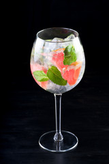gin and tonic alcohol drink cocktail glass ice fruit garnish plain black white background
