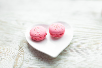 Delicious fresh macaroons on the plate is heart-shaped, lovers