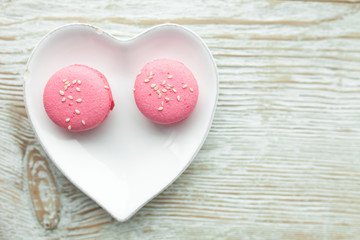 Delicious fresh macaroons on the plate is heart-shaped, lovers