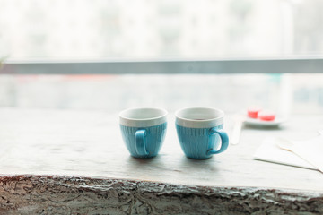 Two cups of blue color, standing on a wooden table, in a cafe, lovers, drinking coffee or tea