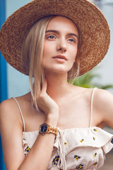 A beautiful young blonde woman exploring pretty part of Chinatown in Singapore. Hot weather in the colorful small urban downtown. She wears casual combination of clothes with a nice hat.