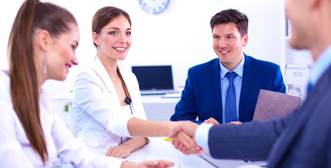 Business people shaking hands, finishing up a meeting, in office