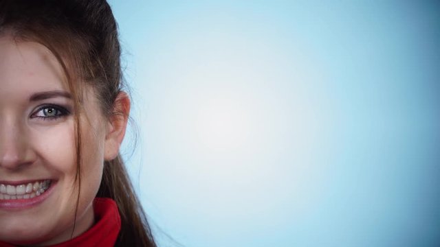 Attractive brunette woman looking at camera and smiling. Cropped view, blue background, copy space 4K ProRes HQ codec