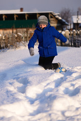 Fototapeta na wymiar Schoolboy boy kicks the ball playing in winter football on the snow cover.