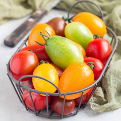 Small colorful cherry tomatoes in metal basket, square format