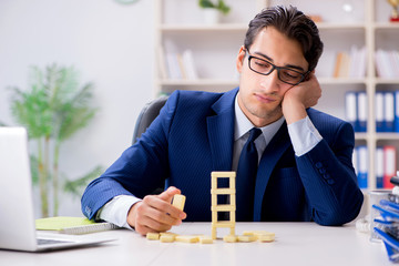 Young businessman building domino tower in office