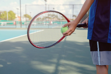 Young boy tennis player on outdoor blue court