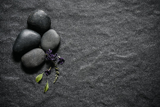black stone with green leaf and smallthe  cute purple flower decoration on stone plate background with copy space for spa and meditation concept background