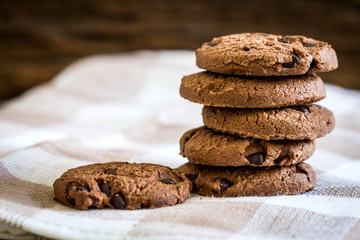 Close up stacked chocolate chip cookies on  napkin with wooden background
