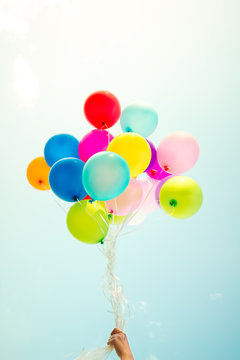 Girl hand holding multicolor balloons done with a retro instagram filter effect, concept of happy birth day in summer and wedding honeymoon party, Vintage color tone style