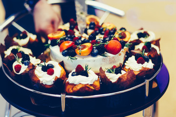 Cake and cupcakes in the center with a large tray with wheels. The man cut the cake. Vintage tonted photo.