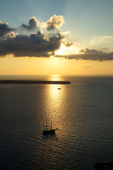 Beautiful sunset scenic ocean view in vast Aegean sea with sailing ship silhouette, abstract cloud and sun beam on shades of yellow and blue sky background
