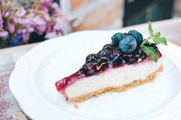A piece of blueberry cheesecake on wooden table.