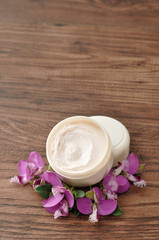 Obraz na płótnie Canvas A tub of hand lotion displayed with small purple flowers