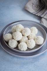 Plate with coconut candies on blue concrete table background.