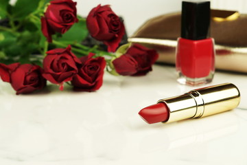 Obraz na płótnie Canvas concept for Valentine's Day, Women day, Mother's day. Red lipstick, nail polish, bouquet of red roses on a marble table.feminine desk, workspace . Close up. Copy space. 