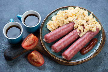 Breakfast with scrambled eggs, beef sausages, tomatoes and coffee, studio shot