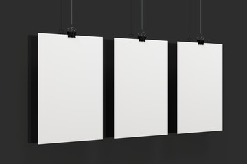 Three blank white posters with binder clip mockup on black background