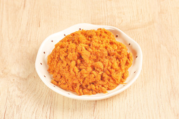 Dried shredded pork in a plate on wooden table.