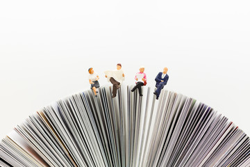 Miniature people, Business team sitting on book, reading news paper,using as background business, education concept.