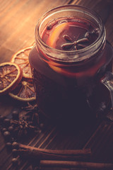homemade mulled wine, dried oranges and cinnamon sticks on a wooden table on a dark background