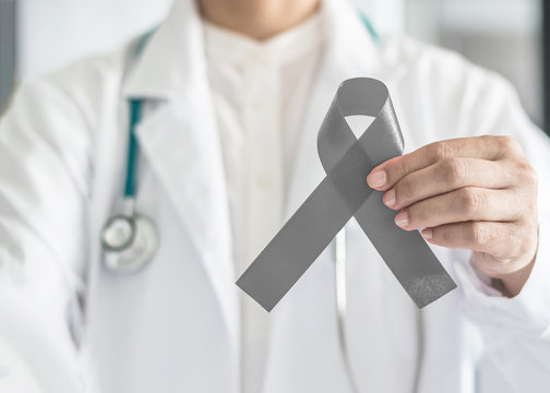 Brain cancer awareness with grey ribbon on doctor's hand, symbolic bow color for Allergies, Alpha-1 Antitrypsin Deficiency, Aphasia, Asthma, Borderline Personality Disorder