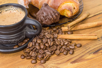 Coffee in black ceramic cup, croissant and chocolate truffle closeup