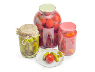 Canned cucumbers and tomato on saucer, jars of canned vegetables