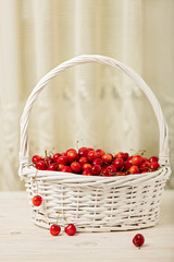 Cherries in a basket on a light wooden background.