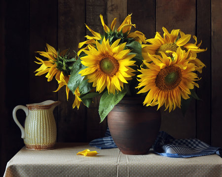 Bouquet of sunflowers in a clay jug on the table.