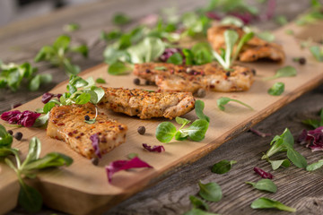 Fresh freshly fried delicious slices of meat on a wooden board with fresh herbs. Appetizing steaks on a wooden board. Still life.
