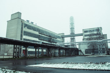 Soviet factory with chimney and tubes in winter.
