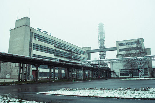 Soviet factory with chimney and tubes in winter.