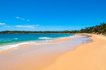 Fototapeta na wymiar Picturesque sand beach with soft waves and blue sky
