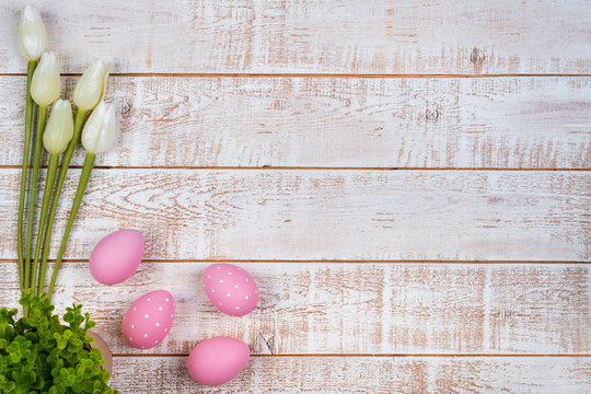 Colorful easter eggs and tulips over white wooden table