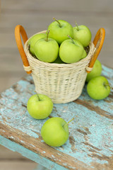 Homemade rustic green apples in a basket on an old stool.