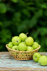 Homemade rustic green apples in a basket on an old stool.