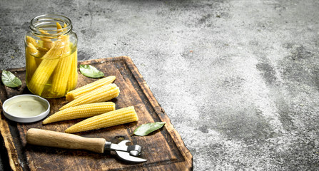 Pickled corn in a jar on a cutting board.