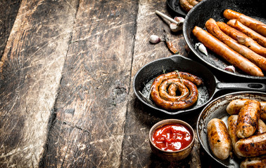 Different sausages in pans with tomato sauce.