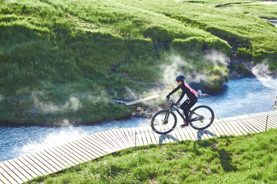 woman cyclist bikes down the slope in the Valley of the river of Hveragerdi Iceland. Hiking Tour of Reykjadalur Hot Springs