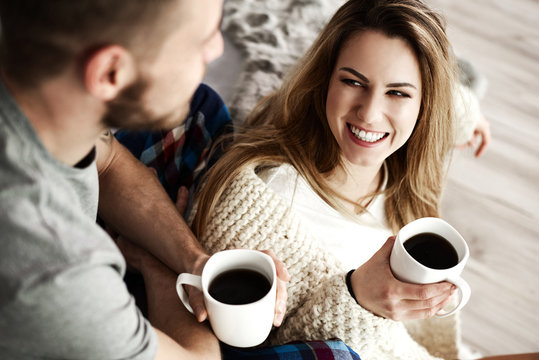 Couple with coffee talking in bedroom