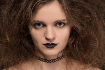 Beautiful girl witch with curly hair on black background for holiday halloween