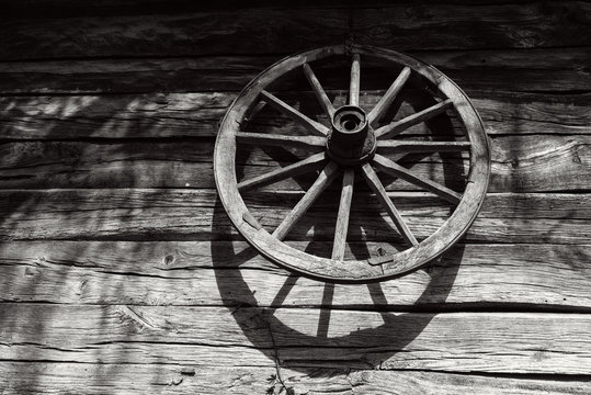 Old wooden wheel on the wall of an antique wooden barn, black and white photo