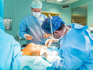 Real surgery team in the operating room. Photos from a live session of breast augmentation surgery. - obrazy, fototapety, plakaty