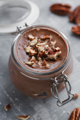 Close-up of chocolate mousse in the glass jar with pecan nuts.