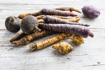 Seasonal root vegetables on a wooden background. 